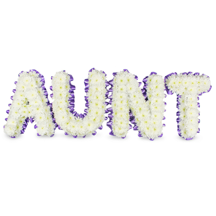 A meticulously designed memorial piece spells AUNT in bold, capital letters, each letter formed from a dense, even carpet of small white spray chrysanthemums. Viewed closely the flowers reveal delicate layers of petals and tiny pale yellow centres that break the white with a whisper of warmth, while the compact planting creates a plush, tactile surface like soft embroidery. Along the perimeter of each letter runs a deep purple satin ribbon, ruffled into a neat scalloped edge that provides a striking, elegant contrast to the white blooms and lends a finished, tailored look. The letters are supported on a solid backing and photographed on a pristine white backdrop so that soft grey shadows fall beneath each form, emphasizing depth and the care taken in construction. There is a subtle, clean scent to the chrysanthemums-a green, slightly dewy aroma-that adds a sensory layer to the visual composition.
Made for moments of remembrance, this arrangement balances reverence with a gentle warmth, intended for funeral services, memorials or private tributes in Mill Hill and surrounding neighbourhoods such as Mill Hill Village and Bittacy Hill. The precise placement of blooms and ribbon reflects a practised hand and a respect for tradition: white for purity and sympathy, purple for dignity and respect. Overall the piece reads as a calm, personalised commemoration, offering families a composed and comforting way to honour a beloved aunt.