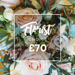 An intimate, overhead portrait of an artisan bouquet that feels almost otherworldly in its softness: large roses in pale blush, creamy ivory and tender peach sit alongside subdued lavender-toned blooms, their petals layered like silk and opening generously toward the light. The scene is breathy and textured - small, lacy white filler blossoms and clusters of tiny pink buds weave delicate filigree between the stronger rose forms, while feathery dried grasses and cream-coloured seed heads add an earthy, nostalgic note. The bouquet's foliage is lush and varied, led by rounded eucalyptus leaves in a subtle, dusty green that frames the composition and adds structural rhythm; other glossy greens push through to create depth and a sense of natural movement. The soft daylight and shallow focus bring forward the tactile pleasure of each petal and the gentle scent one imagines rising from the arrangement: a mix of dewy rose, sweet herb and dried hay. Centered on the image is a clean white rectangular frame that overlays the flowers, carrying refined typography: the words "Florist Choice" in an elegant script with "CHOICE" beneath in a clear, compact sans-serif, and the price shown as "?70" in strong white numerals. This bouquet communicates quiet celebration and refined joy - the kind of hand-selected offering a Mill Hill neighbour might choose for a birthday, thank-you, or to send solace across the road from the green or to a loved one nearby.