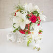 This wedding-style arrangement captures a moment of quiet celebration, with white lilies and red roses gathered into a harmonious dome that would feel perfectly at home in a Mill Hill reception room. At the centre of the bouquet, creamy lilies open wide, each petal gently flaring outward like a dancer's skirt in mid-turn, their soft, velvety surface catching the ambient light. Nestled closely against them, deep red roses unfold in tight spirals, layers of petals forming rich, velour-like cups that suggest passion and dedication. Fine sprays of gypsophila, known fondly as baby's breath, weave between the main blooms, adding airy clusters of tiny, bright white flowers that soften any harsh lines and create a sense of lightness. Glossy hypericum berries in coral-red and crimson peek from between the petals, their rounded shapes adding both visual interest and a joyful, almost festive energy, as if anticipating toasts and laughter along Mill Hill Broadway. Hints of fresh greenery frame the arrangement, providing a subtle backdrop of cool green tones that make the whites and reds appear even more vivid. The bouquet is placed in a simple yet stylish pale container, perhaps woven or lightly textured, reinforcing the feeling of understated elegance. The lighting is calm and diffuse, reminiscent of soft daylight streaming through the windows of a Mill Hill family home just before guests arrive. It is easy to imagine this design as a bridal bouquet, a table centrepiece, or a special anniversary arrangement, radiating love, refinement, and gentle optimism.