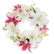 A sophisticated floral tribute designed in Mill Hill, this circular wreath rests against a stark white background, radiating dignity and calm. The arrangement is dominated by bold white lilies, their trumpet-shaped petals stretching outward to reveal gentle green-gold stamens, providing an aura of purity and stirring memories of peace. Between the lilies, flashes of deep fuchsia pink lilies add depth and a sense of joy amidst sorrow, their star-shaped blooms flecked with darker hues. Soft, creamy white and pale blush roses weave through the design, their compact petals contrasting delicately with the more expansive lilies. The addition of muted green leaves, possibly eucalyptus or Mill Hill-fresh foliage, lends the wreath both structure and a sense of place. Crafted into a continuous, unbroken circle, the arrangement symbolises eternal remembrance and the cyclical nature of life. Luminous in careful lighting and vivid against the white backdrop, every bloom and leaf stands out, making the wreath a fitting choice for funeral services, sympathy gestures, or memorial gatherings held within Mill Hill. The effect is both serene and uplifting, an evocative testament to life and memory shaped by the expertise of local florists who understand the nuances of their community.